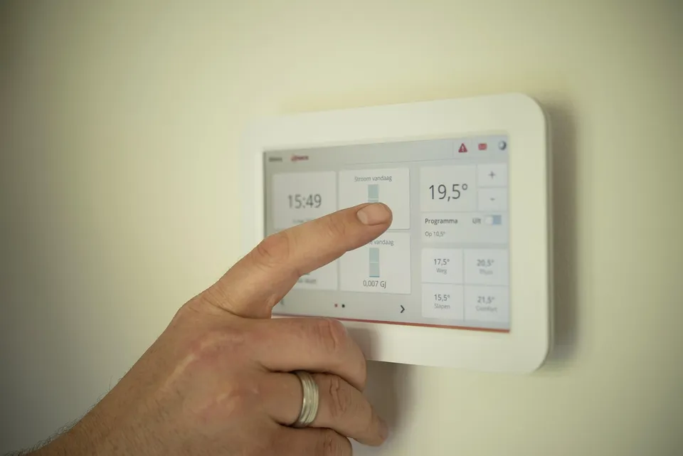 Finger adjusting a wall thermostat